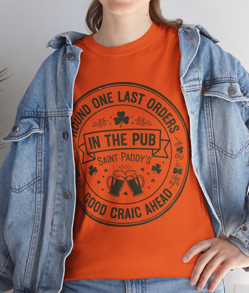 Orange unisex t-shirt featuring the "Good Craic Ahead" pub seal design in dark green. A fun, playful twist on traditional St. Patrick's Day gear, perfect for women or men who want a softer color palette while keeping the Irish drinking humor.