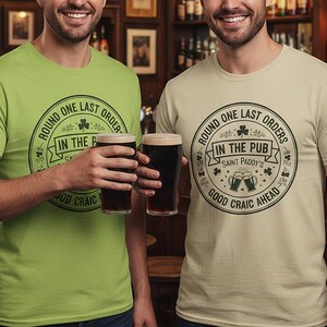 Kiwi Green and Sand Colors unisex crewneck tee with a white or light-colored vintage pub stamp graphic. The "Round One Last Orders" and "Good Craic Ahead" text pops against the green fabric, creating a monochromatic Irish look perfect for St. Paddy's Day parades and pub crawls.