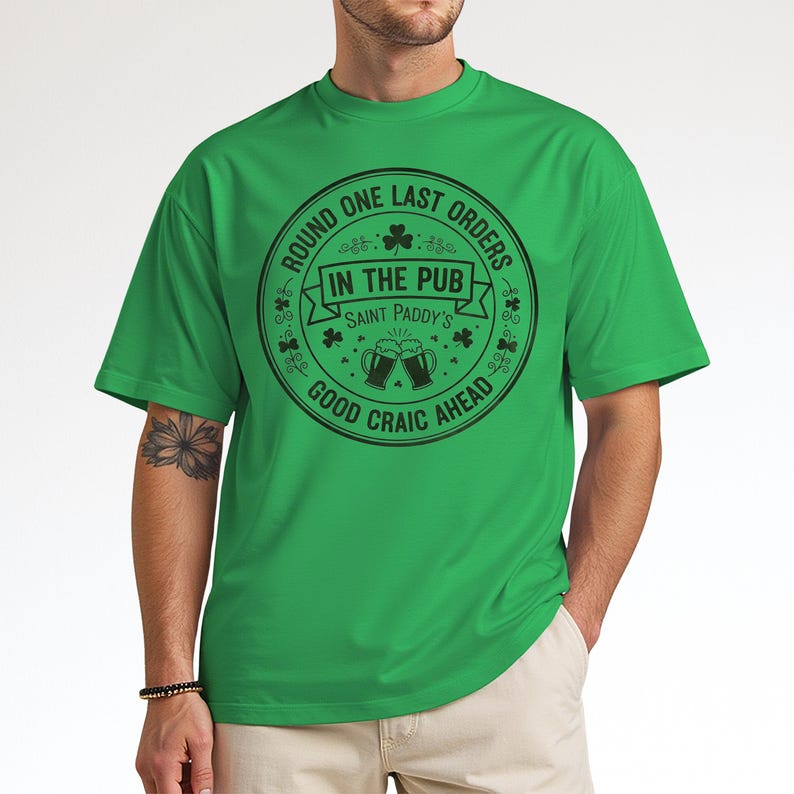 Green unisex crewneck tee with a white or light-colored vintage pub stamp graphic. The "Round One Last Orders" and "Good Craic Ahead" text pops against the green fabric, creating a monochromatic Irish look perfect for St. Paddy's Day parades and pub crawls.