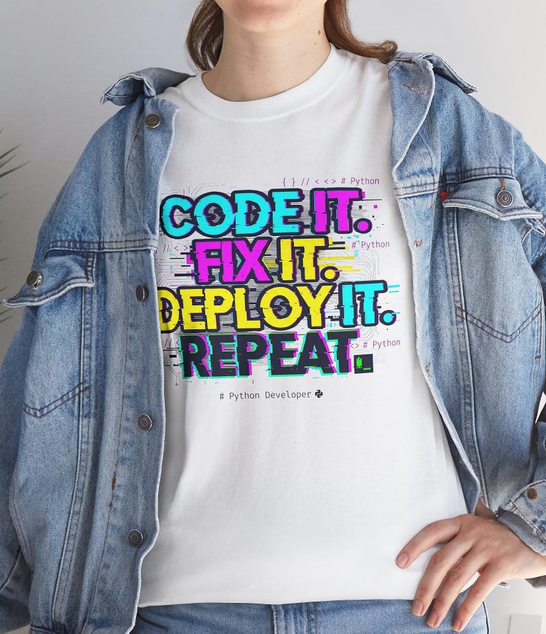 White t-shirt with a neon glitch typography design: "CODE IT. FIX IT. DEPLOY IT. REPEAT." and "# Python Developer". Gritty, modern streetwear for programmers and engineers.