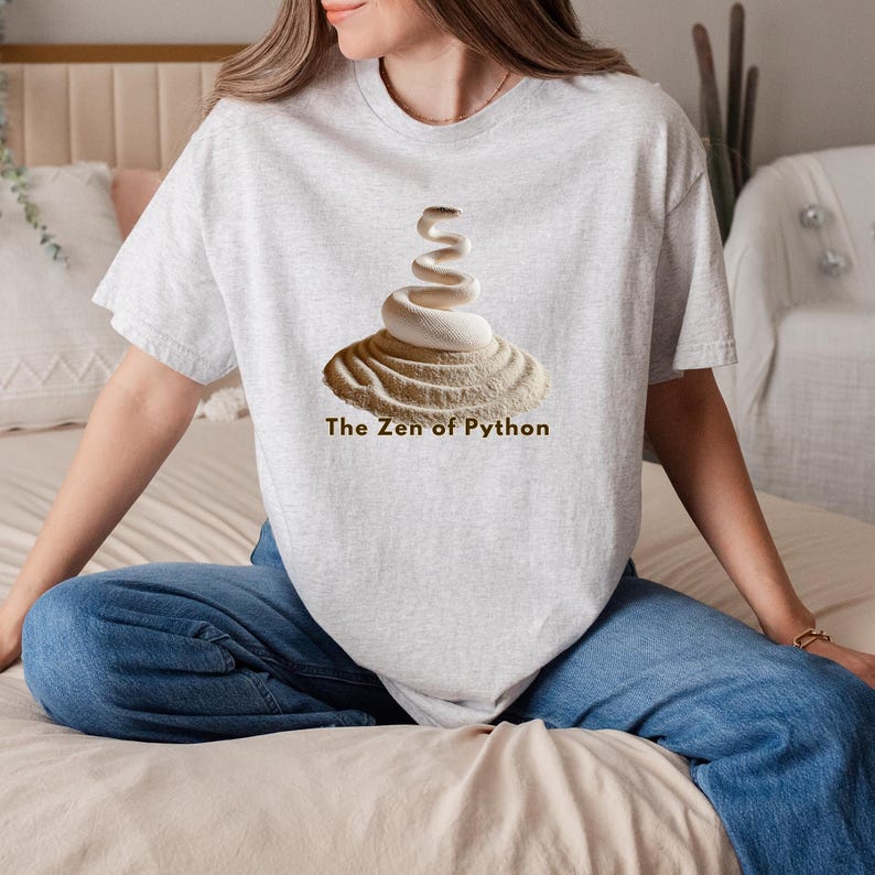ash grey t-shirt with an elegant minimalist print of a white coiled python on a raked sand garden. "The Zen of Python" text below. Aesthetic tech apparel for programmers and computer science grads.