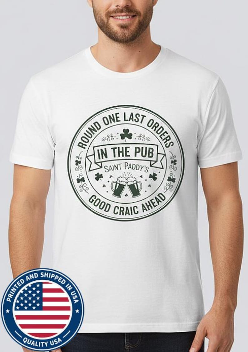 White unisex t-shirt featuring a vintage green circular Irish pub logo design. The text reads "Round One Last Orders / In The Pub / Saint Paddy's / Good Craic Ahead" surrounding two clinking beer mugs and shamrocks. Clean, classic look for St. Patrick's Day.