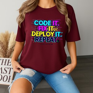 Maroon shirt with a bright professional glitch print. A funny and stylish gift for software developers and tech leads. Features a bold repeat cycle coding mantra.