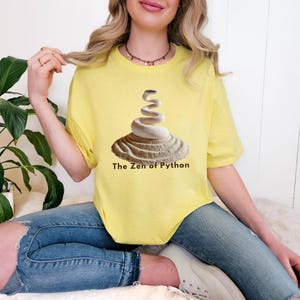 Cornsilk t-shirt featuring a detailed white python snake in a serene Zen sand garden. "The Zen of Python" motto for developers. High-end, sophisticated STEM graphic.