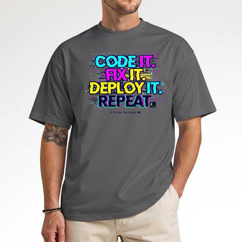 Charcoal grey t-shirt with a neon glitch typography design: "CODE IT. FIX IT. DEPLOY IT. REPEAT." and "# Python Developer". Gritty, modern streetwear for programmers and engineers.