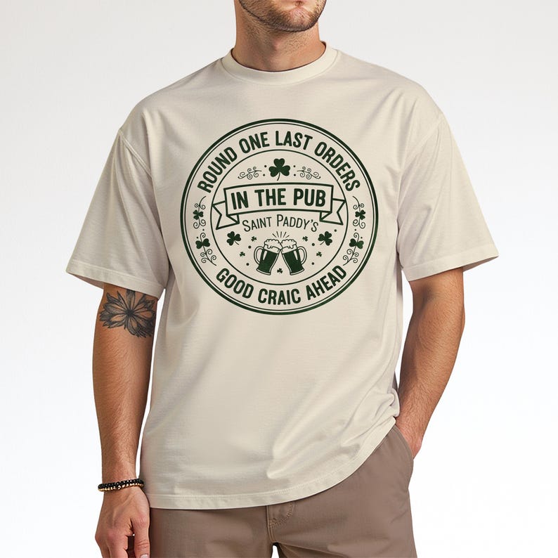 Sand beige unisex t-shirt with a dark green "Last Orders In The Pub" emblem. The vintage-style beer mug graphic and shamrock details give it a retro, worn-in Irish bar feel, ideal for a casual, understated St. Patrick's Day outfit.