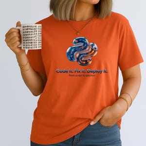 Orange t-shirt with a high-contrast 3D liquid python graphic. The glowing internal code highlights the "Code it. Fix it. Deploy it." motto. Energetic and eye-catching gift for tech-savvy graduates and software developers.