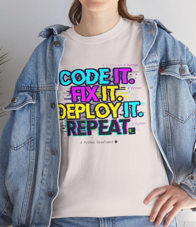 Ice grey t-shirt with a neon glitch typography design: "CODE IT. FIX IT. DEPLOY IT. REPEAT." and "# Python Developer". Gritty, modern streetwear for programmers and engineers.