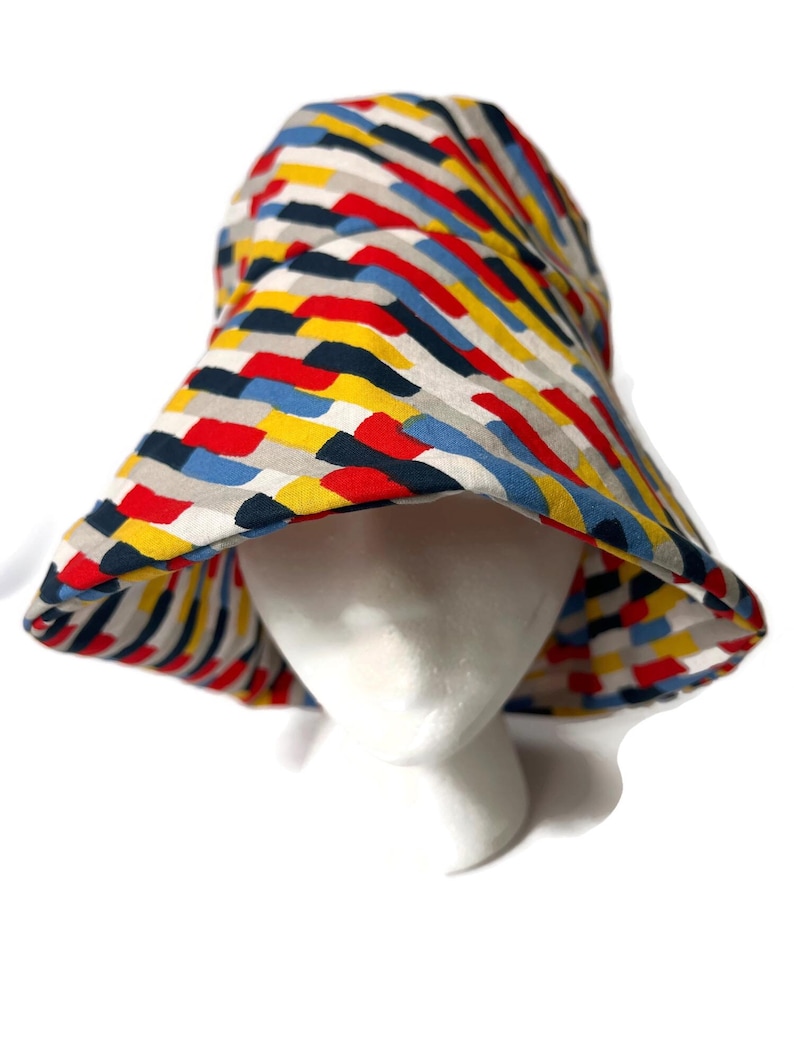 May include: A wide-brimmed bucket hat with a colorful geometric pattern in shades of red, yellow, blue, and gray.