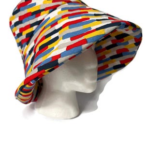 May include: A bucket hat with a colorful geometric pattern in shades of red, blue, yellow, and gray. The hat is made of fabric and has a wide brim.