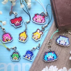May include: A collection of nine clear acrylic charms featuring pixel art characters with vibrant hair colours including red, pink, yellow, green, blue, and teal. Each charm is attached to a small metal lobster clasp and a colourful nylon cord loop.