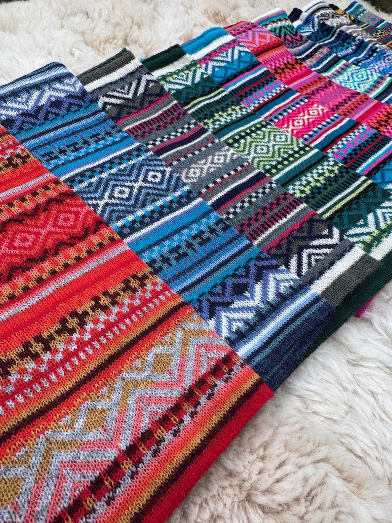 May include: A collection of colorful knitted textiles with geometric patterns. The textiles feature a variety of colors, including red, blue, green, and pink, with white and gray accents. The patterns include diamonds, zigzags, and stripes.