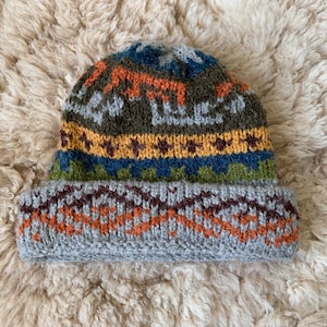 May include: A gray, brown, blue, green, and yellow knitted hat with a geometric pattern.