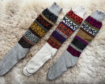 May include: Three pairs of long, grey, white and multi-coloured patterned socks with geometric designs. The socks are made of wool and have a traditional look.