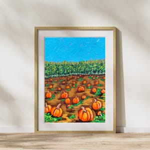 May include: A painting of a field of pumpkins in a fall landscape. The pumpkins are orange and the field is brown. There are green trees in the background and a blue sky.