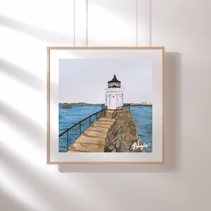 May include: A watercolor painting of a white lighthouse with a black roof and a stone walkway leading to it. The lighthouse is on a small island with blue water surrounding it. The painting is framed in a light wood frame.