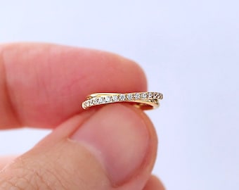 Puede incluir: Un delicado anillo de oro con una fila de pequeños diamantes engastados en una banda curva.