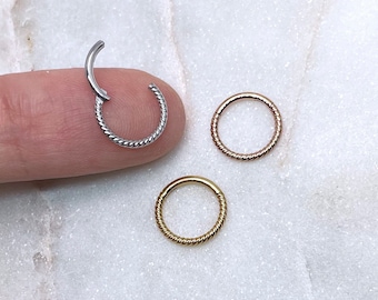 May include: Three small, circular hoop earrings in silver, rose gold, and gold. Each earring features a twisted rope design around the outer edge. One silver earring is open, while the others are closed.