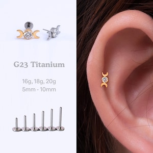 May include: A gold triple moon cartilage piercing with a clear gem in the center. The piercing is made of G23 titanium and is available in 16g, 18g, and 20g. The length of the piercing is 5mm to 10mm.