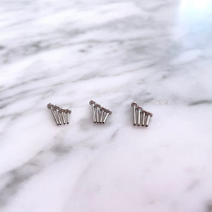 May include: Three sets of five silver-toned, small, round-headed, metal studs.