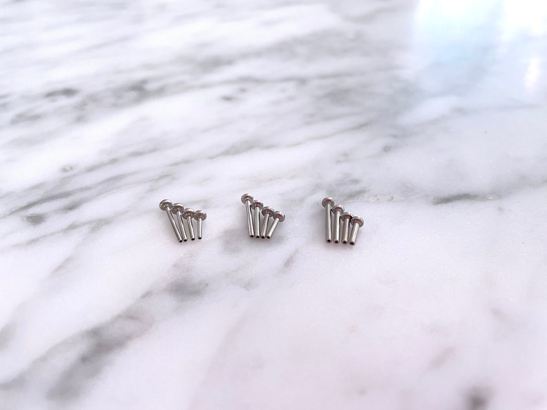 May include: Three sets of five silver-toned, small, round-headed, metal studs.