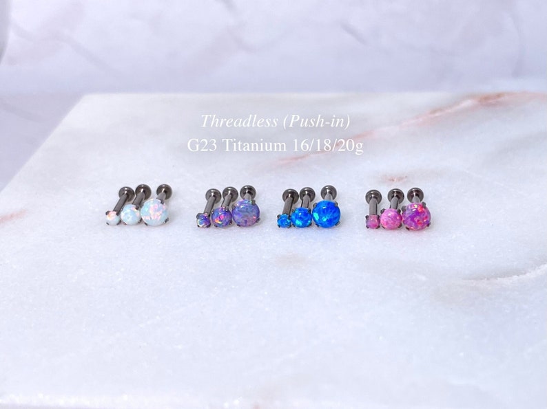 May include: Several sets of threadless push-in earrings with opalescent stones in various colors, including white, purple, blue, and pink. The earrings are made of G23 titanium and are available in 16, 18, and 20 gauge sizes.