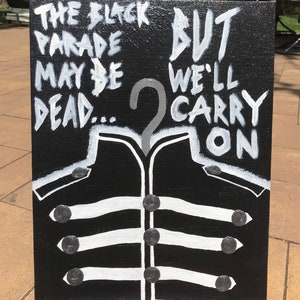 May include: Black canvas art with white text and a stylized jacket design. The text reads "The Black Parade May Be Dead... But We'll Carry On." The jacket design features white stripes and black buttons.