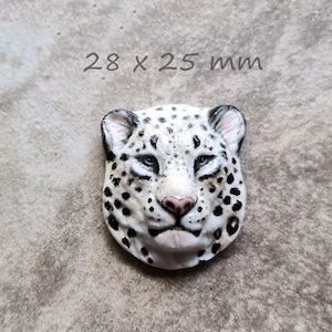 Op de afbeelding: Een wit en zwart luipaardhoofdsculptuur met een roze neus en zwarte vlekken. De sculptuur is 2,8 x 2,5 cm. De tekst "28 x 25 mm" staat boven de sculptuur.