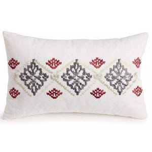 May include: White rectangular pillow with embroidered geometric patterns in gray, red, and light gray. The pillow features a repeating diamond design with floral accents, suitable for home decor.