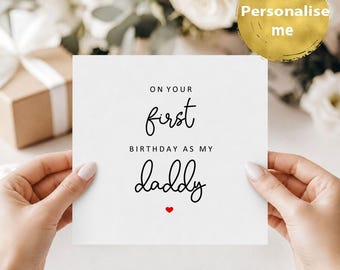Puede incluir: Una tarjeta de felicitación cuadrada de color blanco con texto en negro que dice ON YOUR first BIRTHDAY AS MY daddy, con un pequeño icono de corazón rojo centrado en la parte inferior. La tarjeta tiene un diseño limpio con una fuente combinada.