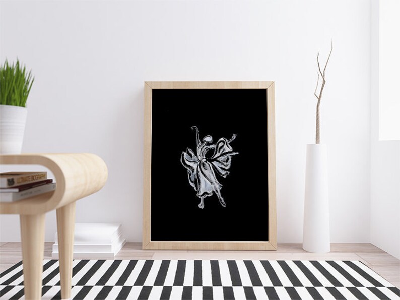 Pode incluir: Uma ilustra&ccedil;&atilde;o em preto e branco de uma bailarina com um vestido fluido, enquadrada em uma moldura de madeira e exposta em uma parede branca.