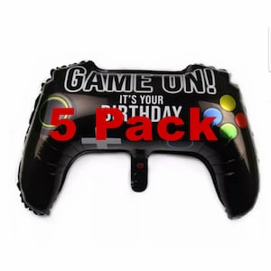 Op de afbeelding: Vijf zwarte en witte gamecontroller-vormige folie ballonnen met de tekst "Game On! It's Your Birthday" en "5 Pack" in rood.
