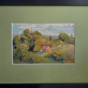 May include: Oil painting of a landscape with a small house and trees, framed in black with a green mat. The artwork depicts a rural scene with a house nestled among trees, under a cloudy sky. The painting uses warm colors.