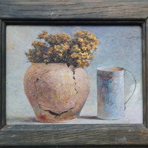 May include: A still life painting of a cracked terracotta pot with yellow flowers and a blue metal mug. The painting is framed in a dark wood frame.