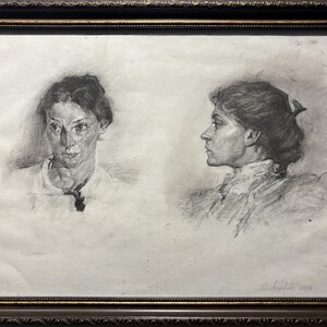 May include: A framed charcoal drawing with two studies of a woman's portrait. One is a frontal view, the other a profile. The artwork is in shades of grey and black, within a dark brown ornate frame.