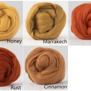 Op de afbeelding: Vijf ronde bundels wolvilt gerangschikt in een raster. De kleuren zijn gelabeld als Honey, een helder geel; Marrakech, een goudbruin; Pumpkin, een levendig oranje; Rust, een diep roodachtig oranje; en Cinnamon, een warm medium bruin.