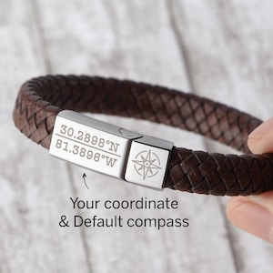 May include: A brown leather bracelet with a silver clasp engraved with coordinates and a compass. The coordinates are 30.2898°N 81.3896°W.