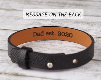 May include: Black leather bracelet with a brown leather interior. The interior is engraved with the text "Dad est. 2020".
