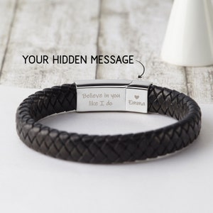 May include: Black leather bracelet with a silver clasp. The clasp has an engraved message that reads "Believe in you like I do Emma" with a heart symbol.