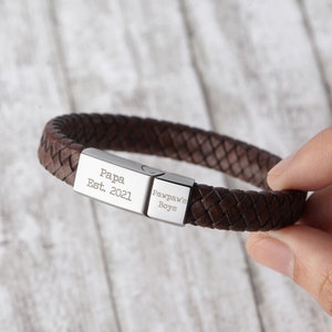 May include: Brown leather bracelet with a silver clasp engraved with "Papa Est. 2021" and "Pawpaw's Boys".