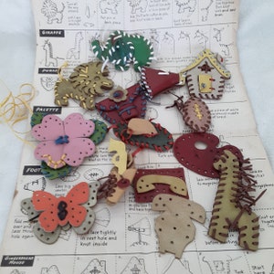 May include: A set of leather craft projects for children. The projects include a giraffe, purse, palette, foot, butterfly, phone, and a house. The instructions are printed on a sheet of paper with illustrations.