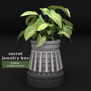May include: A gray, decorative jewelry box with a hidden compartment, designed to resemble a planter. The box is topped with a green leafy plant. The text "secret jewelry box" and "hidden compartment" are visible.