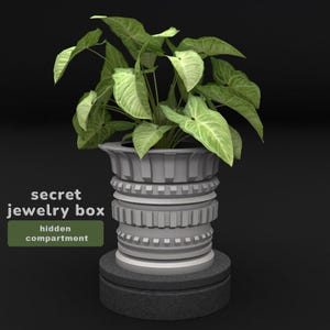 Pode incluir: Uma caixa de joias cilíndrica cinza-clara com um design exterior texturizado e em camadas, contendo um compartimento oculto, encimada por uma planta Syngonium verde. O texto "secret jewelry box" e "hidden compartment" está à esquerda.
