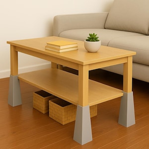 Puede incluir: Una mesa de centro de madera marrón claro con un estante inferior y soportes grises. Dos libros amarillos y una pequeña planta en maceta están encima. Dos cestas tejidas se colocan en el estante inferior. La mesa mide unos 100 cm de largo.