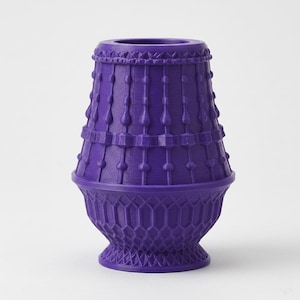 May include: A vibrant purple vase featuring a tapered cylindrical top section adorned with vertical beaded columns and a wider, rounded base section decorated with a textured, repeating honeycomb lattice pattern throughout the lower exterior.