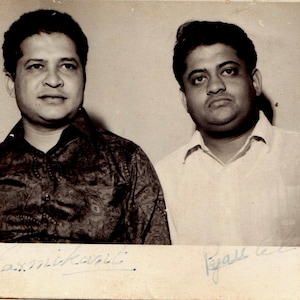 May include: Black and white photo of two men standing side by side. The man on the left is wearing a patterned shirt and the man on the right is wearing a white shirt. Both men are smiling and have their signatures below their images.