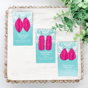 May include: Three pairs of pink leather earrings on white cards with the text "Fleece & Fancy Kristin Rice Handmade Gifts Made in Michigan -Always sterling silver ear wires- "