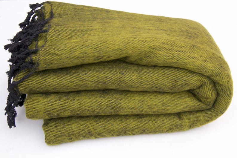 Pode incluir: Cobertor verde-oliva dobrado com franjas pretas. O cobertor &eacute; feito de um tecido texturizado e est&aacute; cuidadosamente empilhado. A franja escura adiciona um detalhe contrastante &agrave; borda do cobertor. Um t&ecirc;xtil dom&eacute;stico aconchegante.