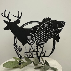 May include: Black silhouette cake topper featuring a deer and a fish with the words "Happy Birthday" in a circle.