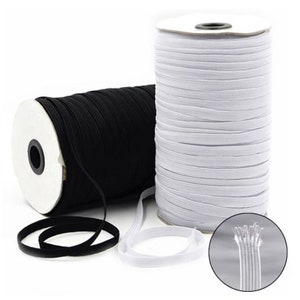 Peut inclure: Deux bobines de cordon élastique, une noire et une blanche, sont enroulées autour de bobines en carton. Le cordon élastique est présenté déroulé dans le coin inférieur droit de l'image.